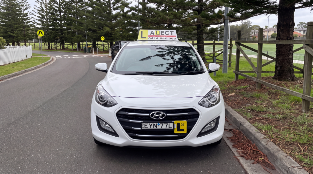 White learner driver car with L plates parked on a quiet road
