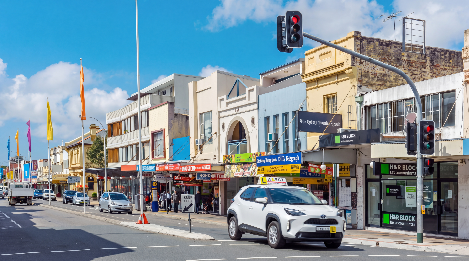 Busy town road with shops, traffic lights and cars, suitable for learner driver road awareness training